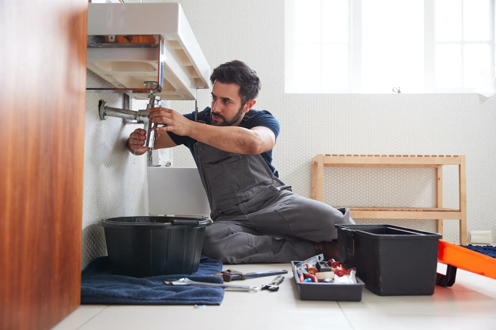 Plumbing Services | Drainage & Plumbing Ltd 1 Plumber fixing a leaking sink in a home bathroom
