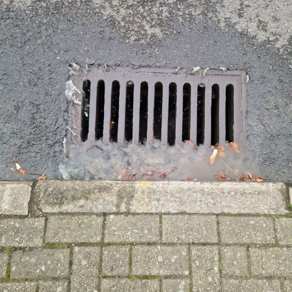 A Drainage & Plumbing LTD engineer using high-pressure water jetting to clear heavy grease and fat from a commercial restaurant drain in Brighton.