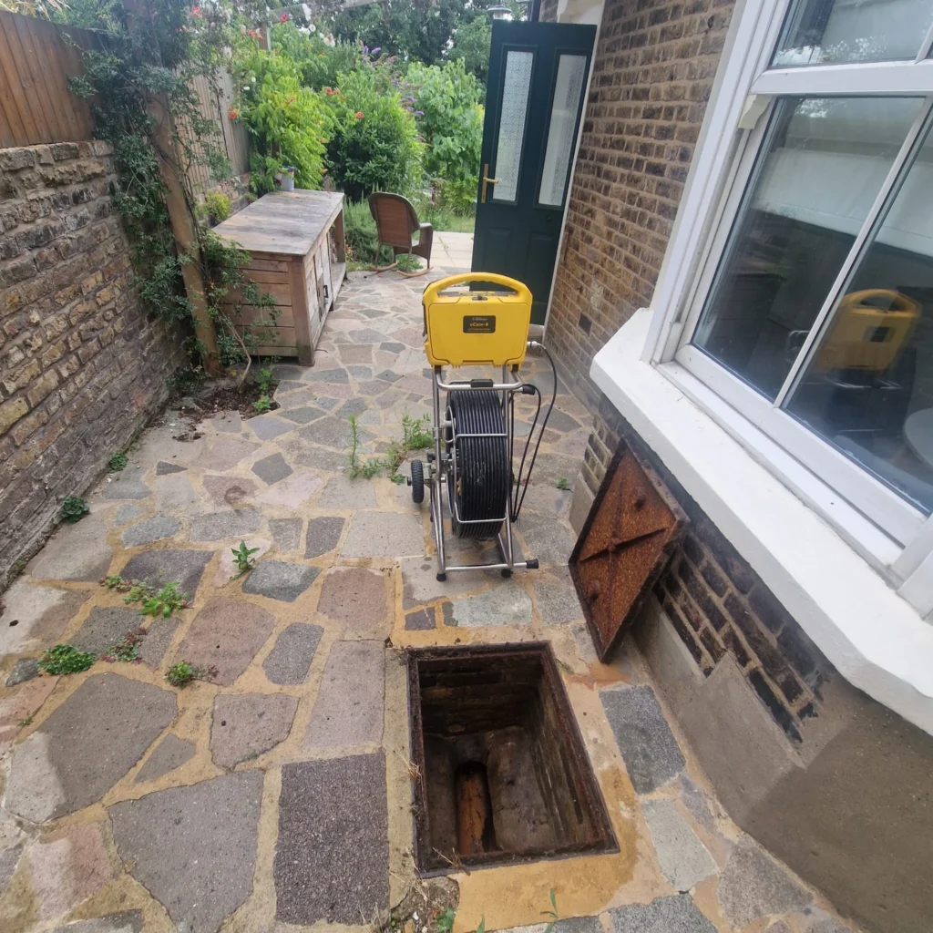 CCTV drain survey equipment set up beside an open inspection chamber during a drain inspection.
