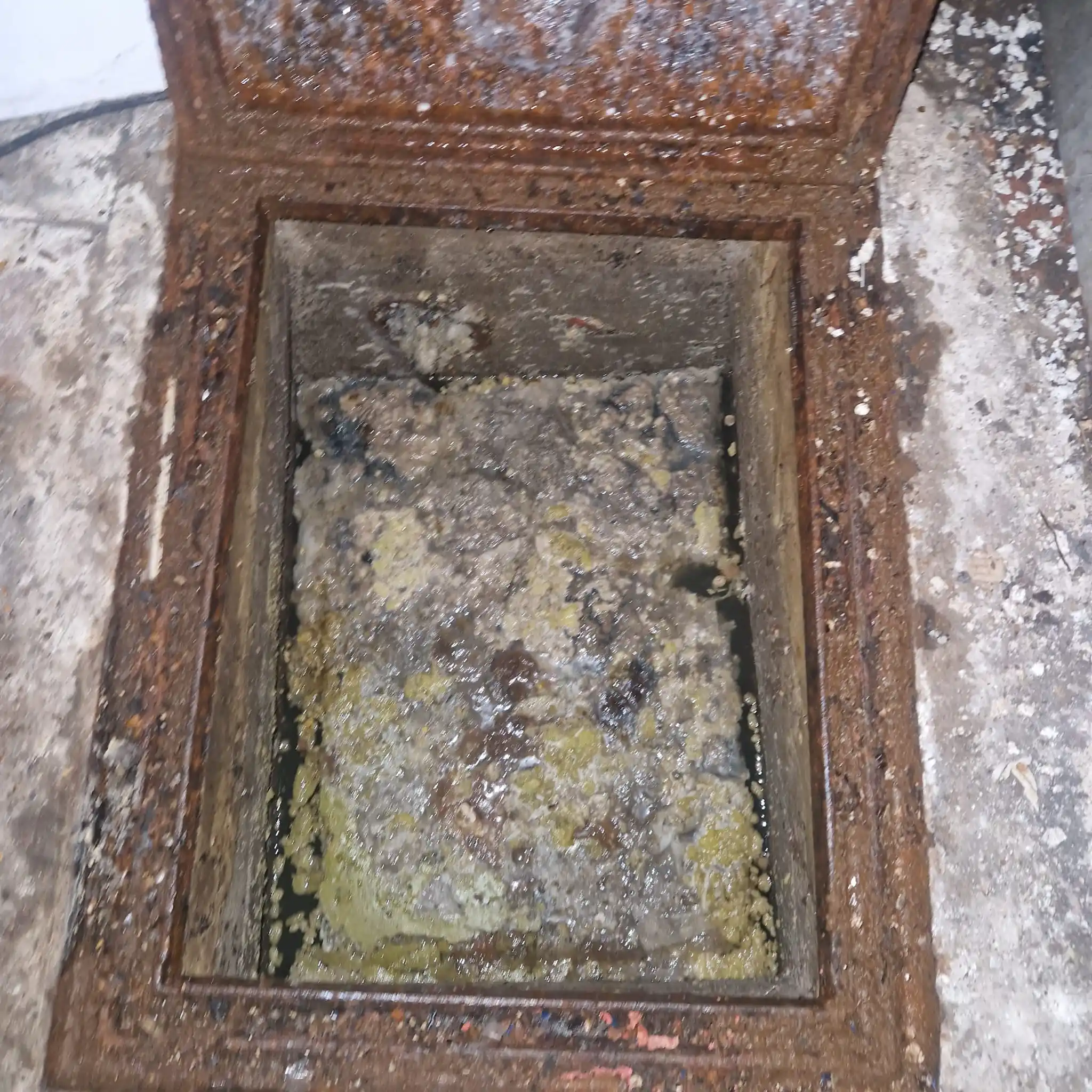 blocked manhole cover with sewage overflow visible, illustrating the result of an untreated drain blockage in a Surrey residential property