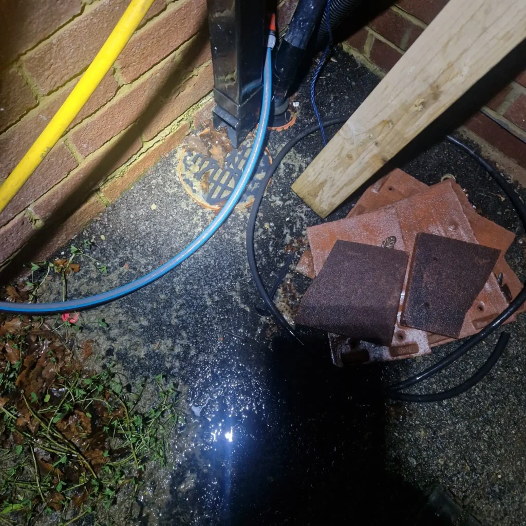 Real photo of an open manhole cover in a garden used to check for a collapsed drain issue or blockage.