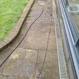A severely blocked channel drain full of mud and debris on a UK driveway needing professional drain cleaning.