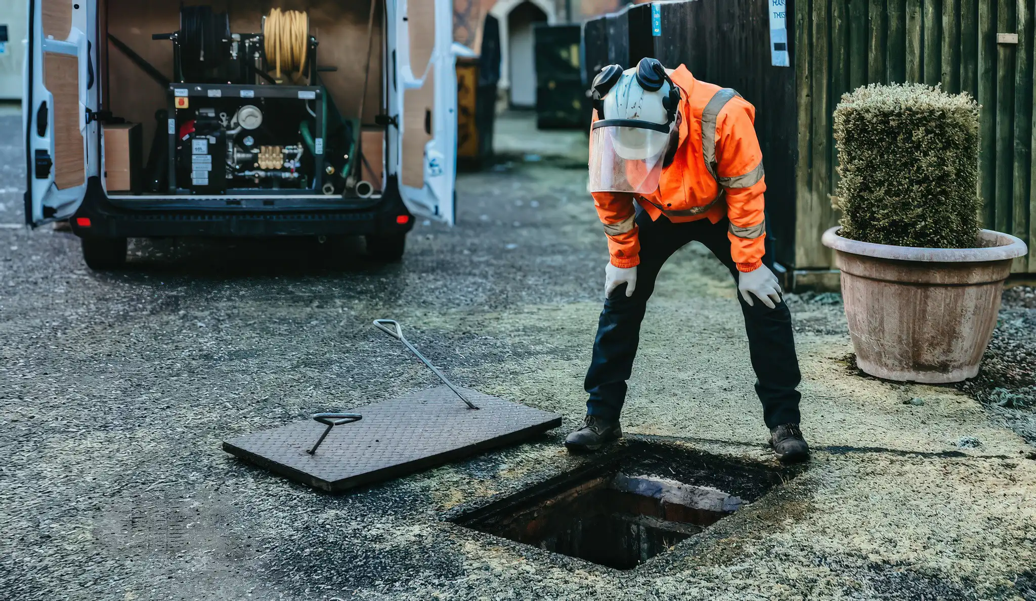 blocked drain clearance — engineer unblocking an external gulley outside a Victorian terrace in Surrey