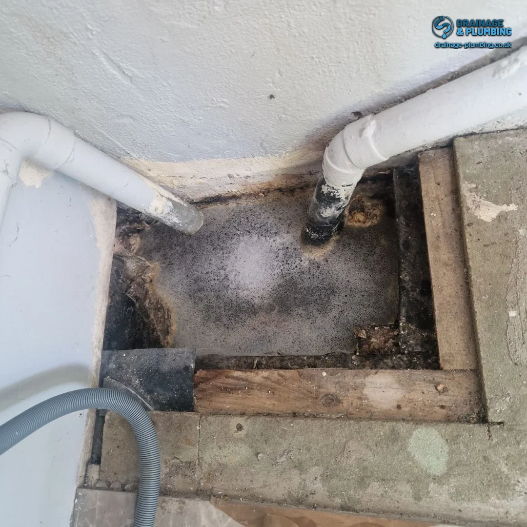 drainage engineer inspecting a residential drain joint for summer heat pipe damage in a South London garden