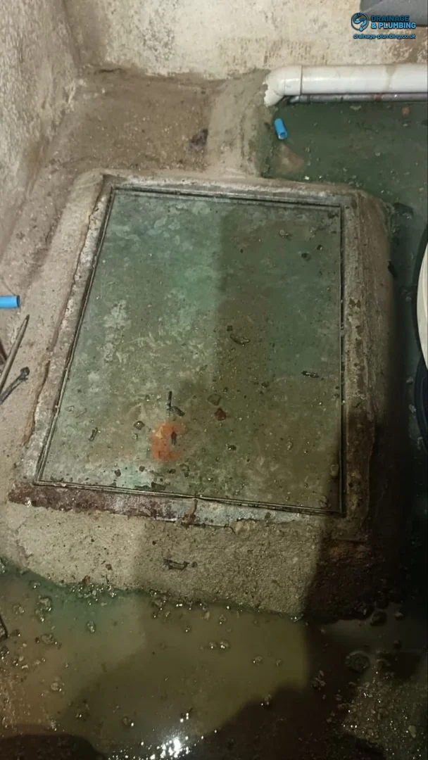 engineer unblocking an outside gully drain choked with silt and debris outside a South East England property