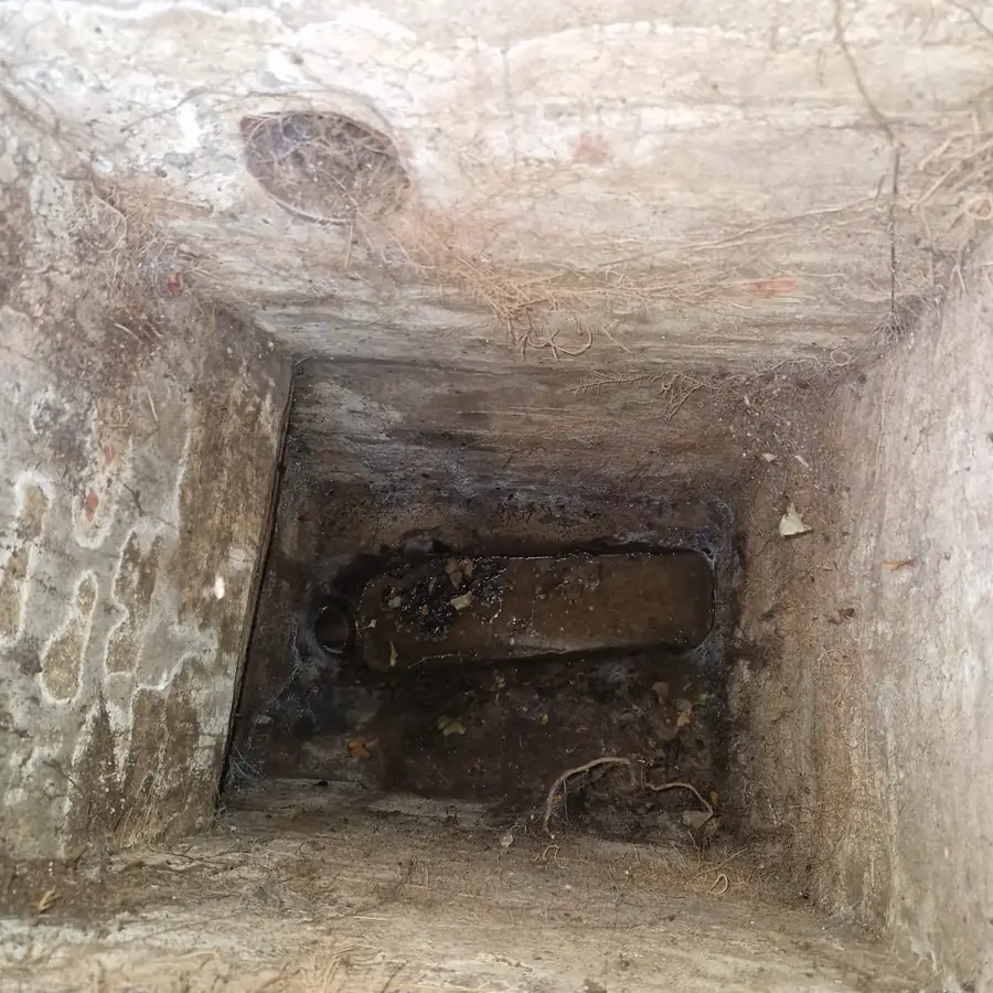 Brick inspection chamber with silt built up over the channel, blocking the flow